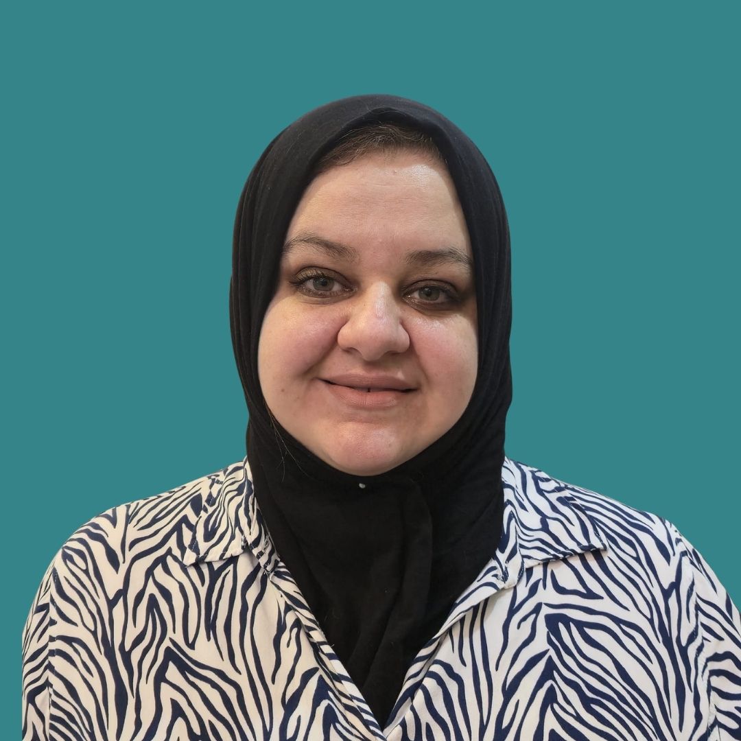 Portrait of a smiling woman wearing a black hijab and zebra-pattern blouse against a teal background