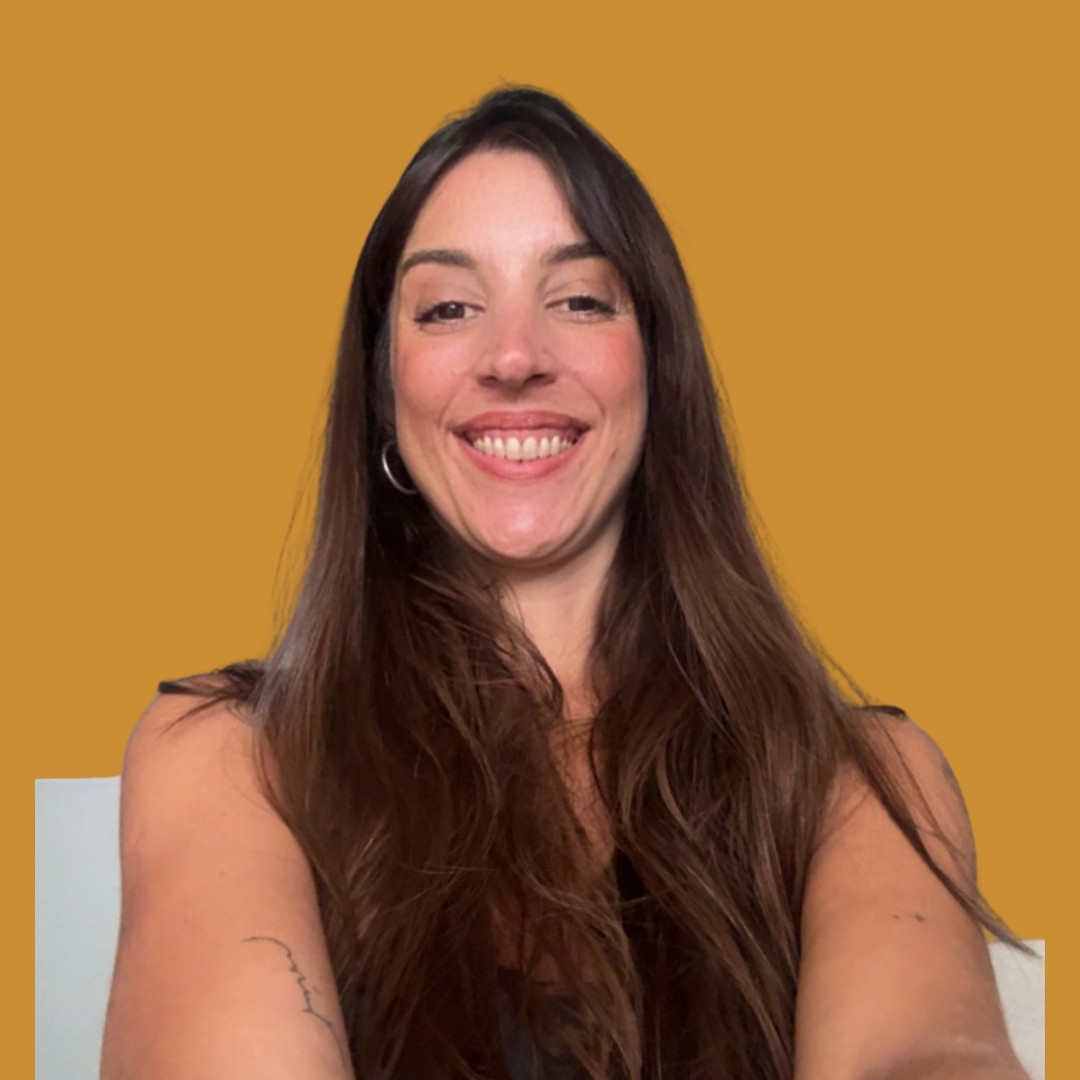 Woman with long brown hair smiling at the camera against a solid orange background.